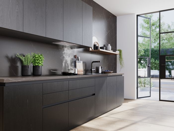 Cucina moderna con cappa integrata sotto pensile, piano a induzione con pentola e vapore, e finestra laterale con vista sul verde