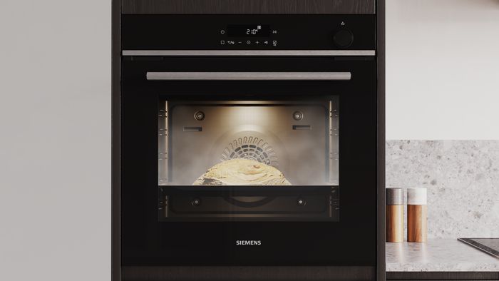 Forno da incasso Siemens con luce interna accesa e teglia con impasto in cottura visibile