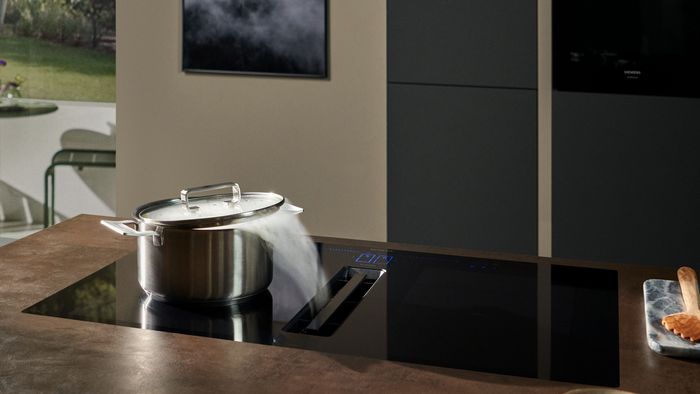 Olla humeante sobre una placa de inducción Siemens, mostrando un ambiente moderno y funcional en la cocina.