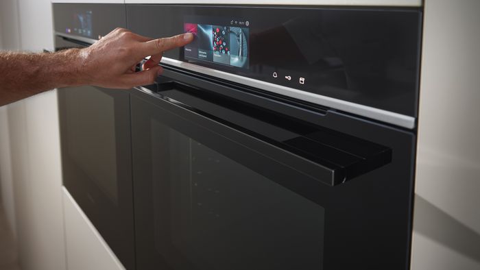 Imagen de ambiente de horno Siemens, con mano tocando el display táctil