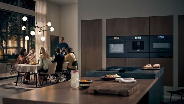 People drinking together with multiple Siemens appliances in kitchen