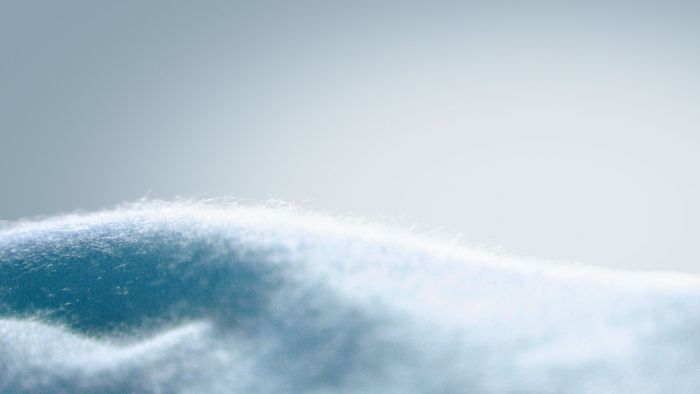 Lana di un tenue blu in primo piano, delicatamente illuminata.