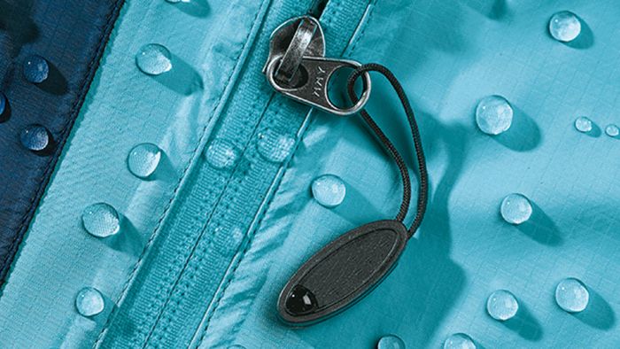 Primo piano della chiusura di un indumento tecnico turchese con alcune gocce d’acqua in superficie