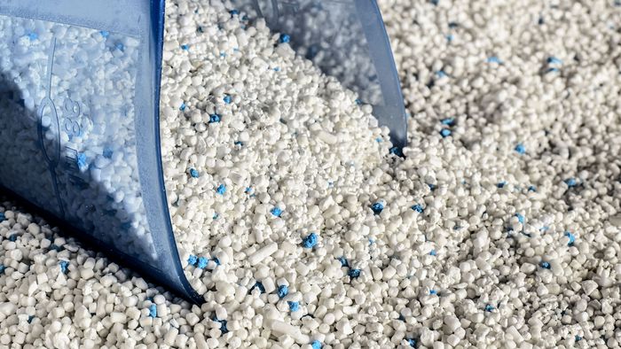 Uma vista aproximada de uma concha de lavar roupa empurrada dentro de detergente em p&oacute;.