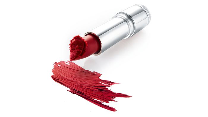 Ein leuchtend roter Lippenstift in einem Chromgehäuse mit einem Schmierschaden von rotem Lippenstift auf der Oberfläche darunter.