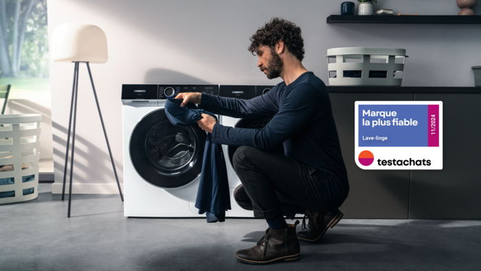 Homme charge machine à laver, intérieur de la maison avec étagères et lampe.