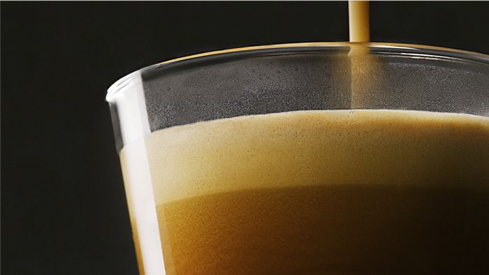 Een close-up van een espressoshot die in een glas wordt geschonken.