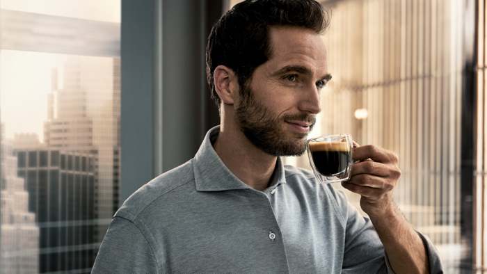 Un homme porte une tasse d'expresso &agrave; ses l&egrave;vres.