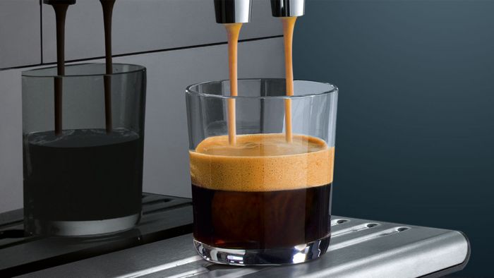 Gros plan sur une machine &agrave; caf&eacute; automatique servant un verre d'expresso.