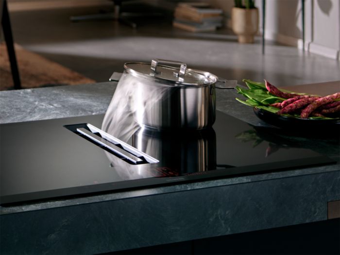 Piano InductionAir della linea studioLine Siemens, pentola in ebollizione e piatto di verdure accanto