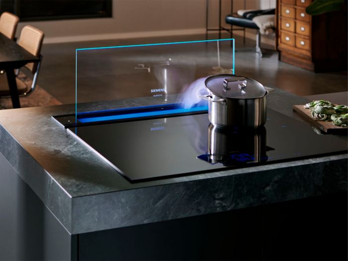 Cappa integrata glassdraftAir della linea studioLine Siemens, con pentola sul piano a induzione e vapore in aspirazione