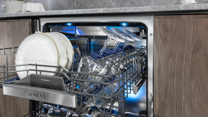 
       En indbygningsopvaskemaskine med &aring;ben d&oslash;r og den &oslash;verste kurv fyldt med tallerkener og vinglas.
      