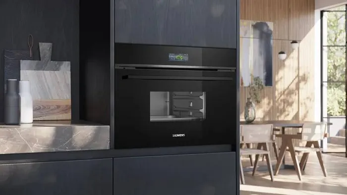 Elegancka i nowoczesna kuchnia ze zintegrowanymi czarnymi piekarnikami marki Siemens, z ekspresem do kawy na g&oacute;rze