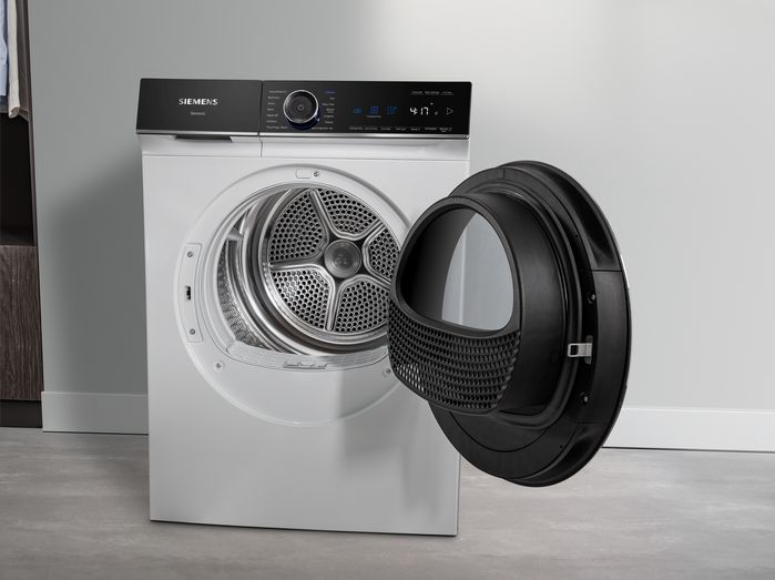 Femme charge des v&ecirc;tements dans la machine &agrave; laver dans l'int&eacute;rieur moderne de la maison.