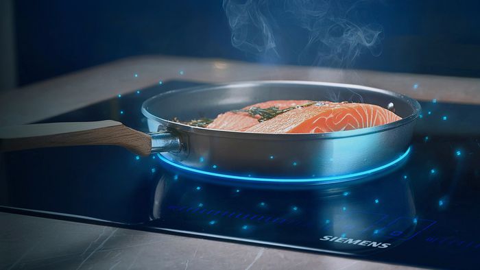 Salmon cooking in pan on induction hob