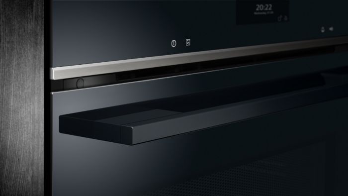 תקריב של דלת תנור אפייה מודרני בצבע שחור. ידית נוחה ומאופקת עם קווים נקיים, לצד מסך מגע שמציג את השעה. העיצוב מינימליסטי ומודרני.