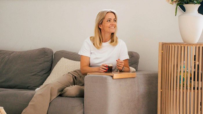 Person sat on sofa with coffee drink on side arm