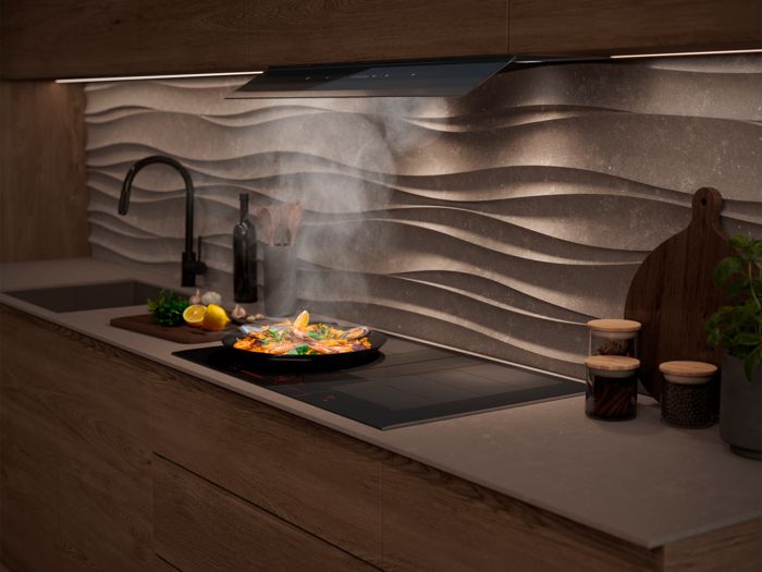 Cucina con cappa Siemens integrata nel pensile, piano a induzione con padella in cottura e vapore in aspirazione