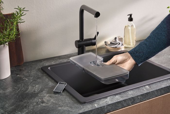 Person som fyller ångugnens vattenbehållare från kranen.