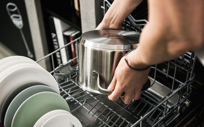 Mani che posizionano una pentola all’interno della lavastoviglie