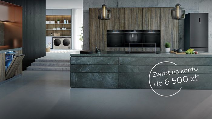 Nowoczesna kuchnia z ciemnymi szafkami, marmurowymi blatami i oświetleniem wisiorek.