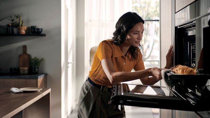 Eine Frau holt ein Backblech aus einem Siemens iQ700 Backofen