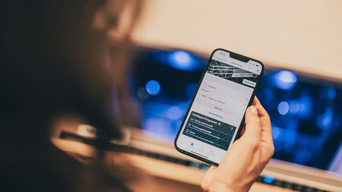 Eine Person nutzt die Siemens Hausgeräte App zur Problemösung per Ferndiagnose auf ihrem Smartphone.
