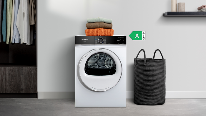 Siemens iQ700 extraKlasse Trockner mit Wäschekorb und gefalteten Pullovern – modernes Design und energieeffiziente Wäschepflege.