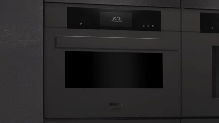 Close-up van een slanke zwarte Siemens inbouwoven met een digitaal display dat de tijd en datum weergeeft, en die modern design belichaamt.   