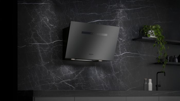 Elegante matzwarte Siemens afzuigkap gemonteerd op een donkere marmeren wand, met slanke designelementen en sfeerverlichting voor een moderne uitstraling. 