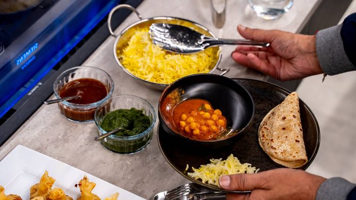 A person is cooking in a kitchen, standing in front of a venting hob.  