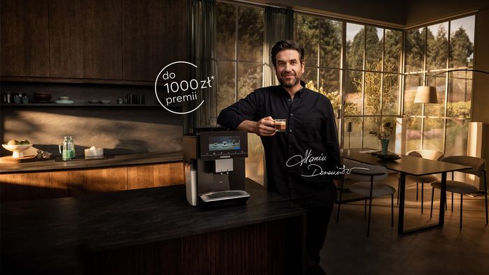 Trzy ekspresy do kawy Siemens na blacie z filiżankami kawy, salon w tle.