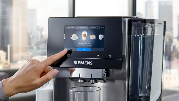יד של אישה מצביע על צג מכונת הקפה של סימנס