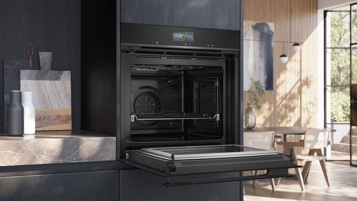 Cucina luminosa con forno da incasso Siemens nero, sportello aperto e interno visibile