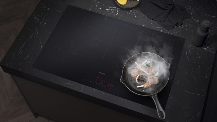 Montaż na równi z blatem płyty grzewczej Matt Edition marki Siemens w blacie z naturalnego ciemnego kamienia.