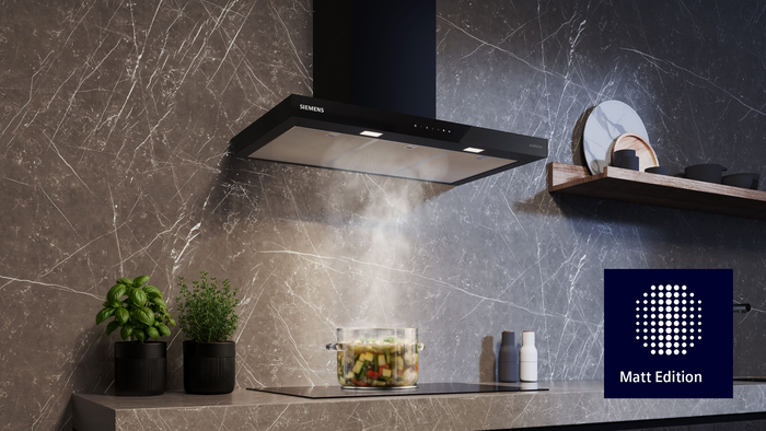 Siemens horizontale Box Wandesse der Matt Edition &uuml;ber einem Induktionskochfeld, kombiniert mit matter K&uuml;che, Steinoptik-R&uuml;ckwand und dunkler Arbeitsplatte.