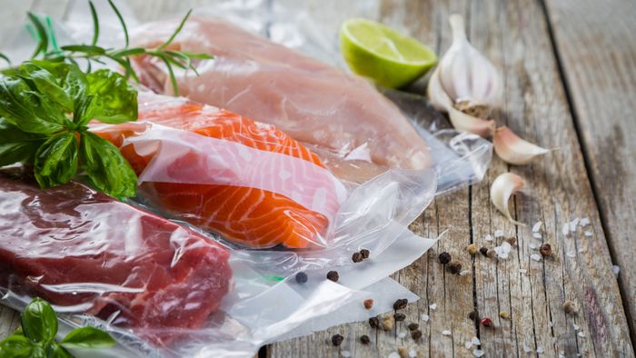 A vacuum sealing machine sealing a piece of meat for storage, showcasing modern kitchen equipment.