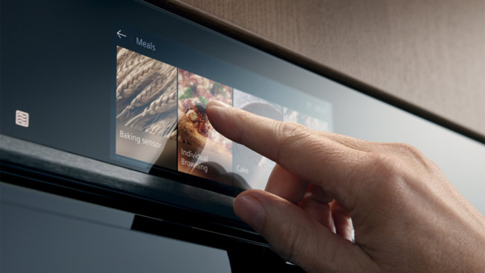 Hand ber&uuml;hrt das Touchdisplay eines Siemens Backofens zur Auswahl einer Backfunktion.