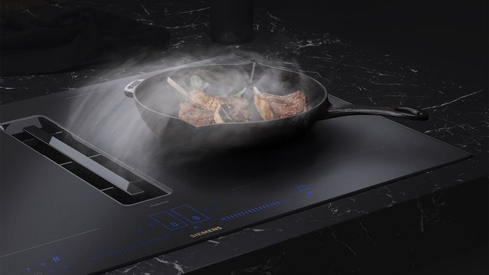 Lamb chops cooking in pan on matt hob with extractor taking away steam