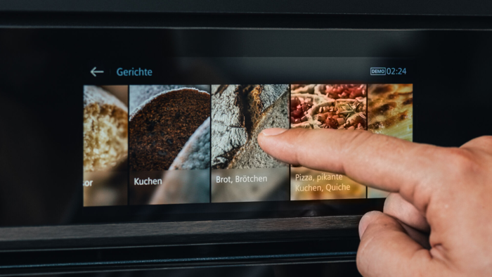 Hand bedient das Touchdisplay eines Siemens iQ700 Backofens und w&auml;hlt die Gerichterkennung f&uuml;r Brot und Br&ouml;tchen aus.