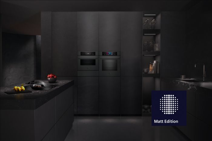 Una cucina moderna ed elegante, con mobili dai toni scuri, elettrodomestici integrati, un piano di lavoro in marmo e frutta fresca a volont&agrave;.