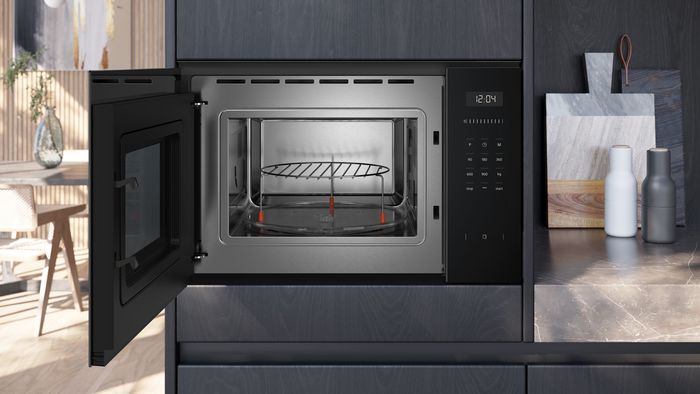 Microonde da incasso Siemens con sportello aperto, teglia con griglia metallica e pannello comandi digitale laterale