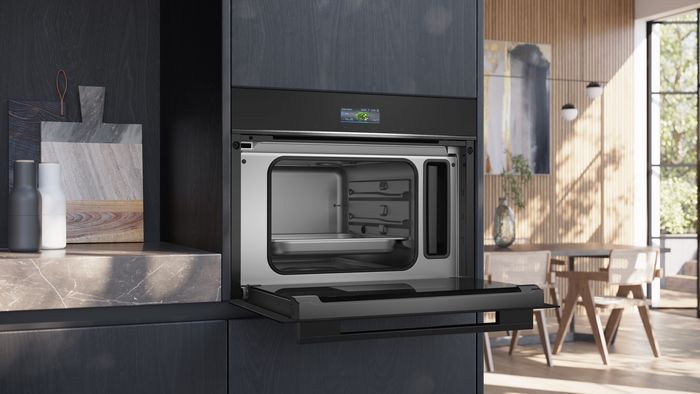 Cucina moderna e luminosa con forno da incasso Siemens, sportello aperto, interno in acciaio inox e display digitale acceso