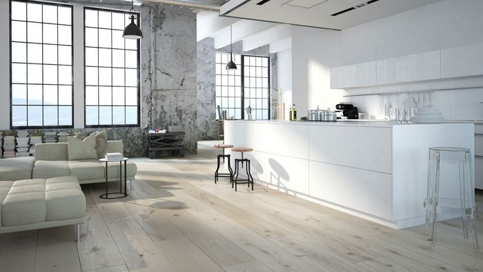 Cucina open space moderna con isola bianca, ampie finestre industriali e zona living luminosa con divano chiaro