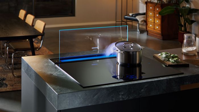 Piano cottura a induzione con cappa telescopica studioLine e pentola in ebollizione, integrato in una cucina dalle tonalit&agrave; calde