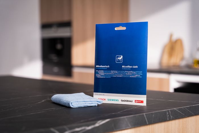 Confezione di panno in microfibra Siemens per la pulizia della lavastoviglie su piano cucina nero, con panno piegato accanto