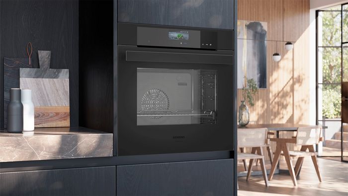 Siemensin musta integroitava uuni on sijoitettu tummaan kaapistoon marmoritasoa vasten; tasolla on leikkuulaudat, ja keitti&ouml; avautuu valoisaan, moderniin ruokailutilaan.     
