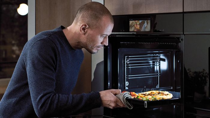 Un hombre introduce una fuente co alimentos en el horno 