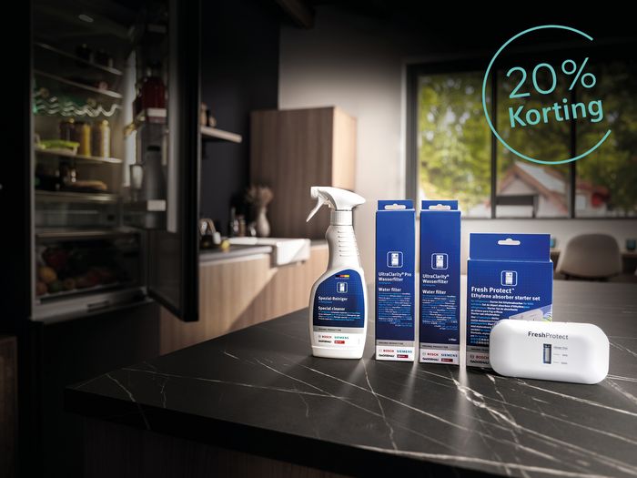 Keukenblad met daarop reinigingsmiddelen voor koelkasten. Koelkast deur staat open.