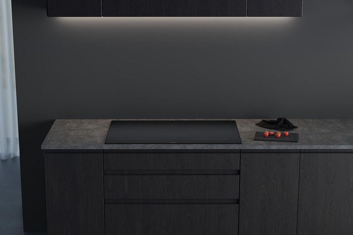         Vue de dessus de c&ocirc;telettes d'agneau cuisant dans une po&ecirc;le en fonte fumante sur une plaque &agrave; induction noire moderne, &agrave; c&ocirc;t&eacute; d'une assiette avec un plat de viande gastronomique et de la pur&eacute;e.       
